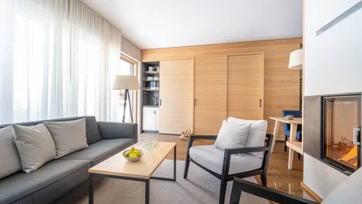 Moderner Wohnbereich mit Sofa, Sesseln, Kamin und Holzverkleidung