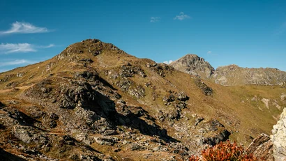 Felsige alpine Berglandschaft unter blauem Himmel mit herbstlicher Vegetation