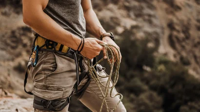 Person mit Klettergurt und Kletterseil in den Händen