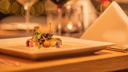 Fine dish and wine glass on set table with warm ambient lighting