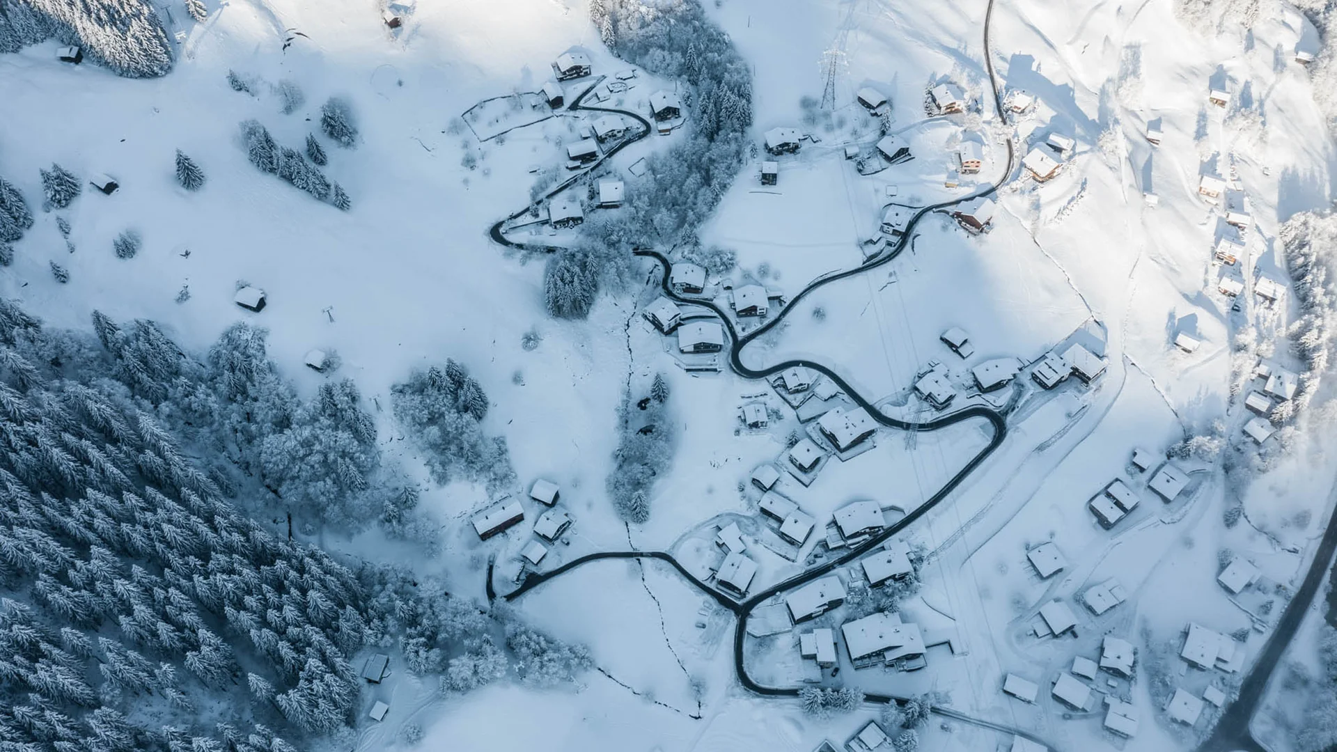 Luftaufnahme eines verschneiten Dorfes mit Straßen und Bäumen