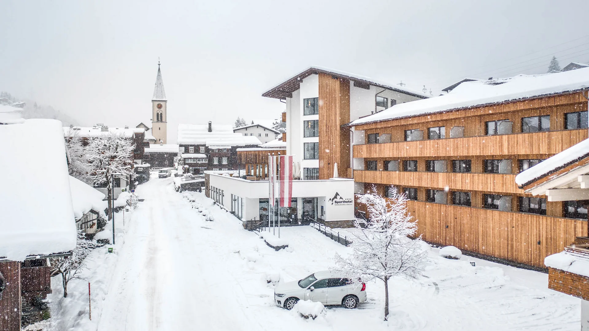 Schneebedeckte Straße mit modernen und traditionellen Gebäuden in einem Dorf