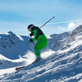 Skifahrer fährt im Pulverschnee an sonnigem Tag in den Bergen