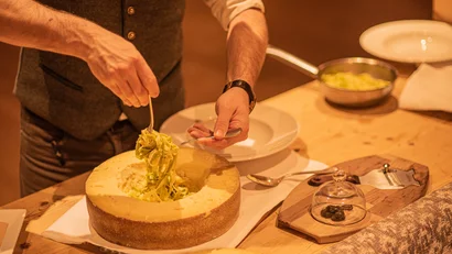 Mann serviert Pasta aus einem ausgehöhlten Käselaib