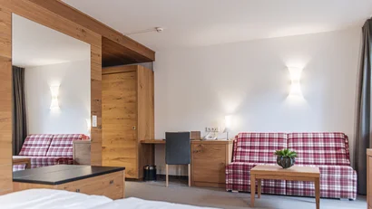 Hotelzimmer mit Holzdekor, kariertem Sofa und Schreibtisch