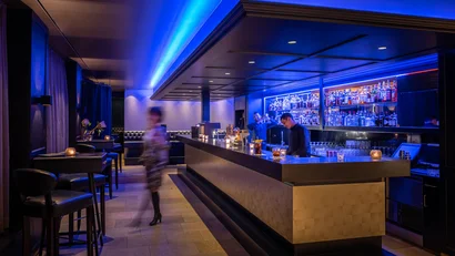 Moderne Bar mit blauem Licht und Barkeepern im Einsatz