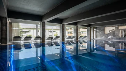 Modernes Hallenbad mit Liegestühlen und großem Fenster