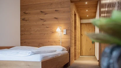 Modernes Schlafzimmer mit Holzwänden und Bett mit weißer Bettwäsche