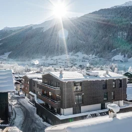 Verschneite Häuser in einem sonnigen Bergdorf