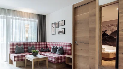 Gemütliche Sitzecke mit kariertem Sofa und Blick ins Schlafzimmer