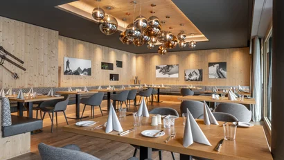 Moderner Gastraum mit Holzmöbeln und goldfarbenen Hängelampen