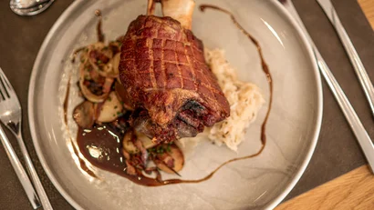 Gebackene Schweinshaxe mit Soße und Beilagen auf einem Teller serviert