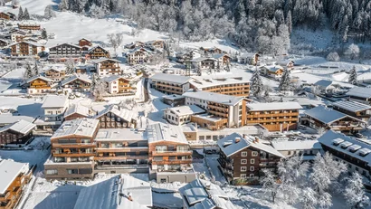 Verschneite Dorfhäuser und Wald in einer Winterlandschaft