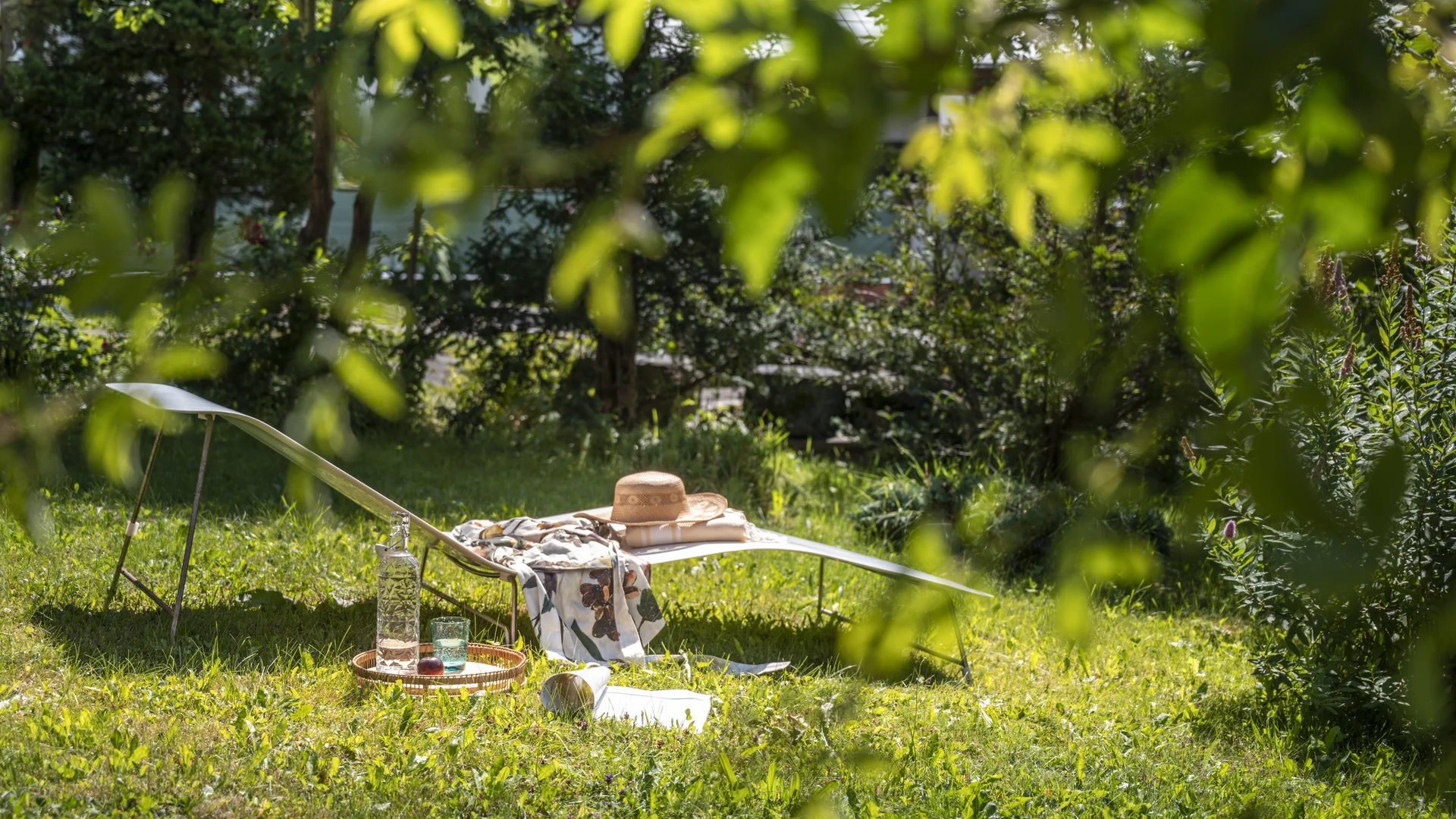 Lounge chair with hat and drinks in sunny garden