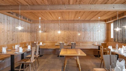 Gemütlicher Holzrestaurantinnenraum mit gedeckten Tischen und Stühlen