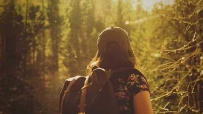 Frau mit Rucksack wandert im sonnigen Wald