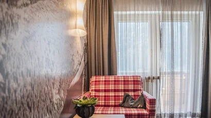 Gemütlicher Sessel mit rotem Karomuster neben Fenster mit Vorhängen