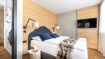 Modernes Schlafzimmer mit Doppelbett, blauen Kissen und Wand-TV