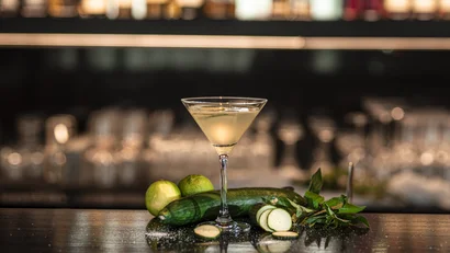 Cocktailglas mit Gurken- und Limettenfrüchten auf Barhintergrund