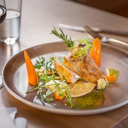 Fein angerichtetes Hähnchengericht mit Gemüse und Rotwein