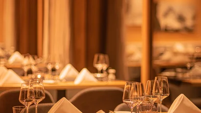 Gemütlich gedeckte Tische mit Gläsern und Servietten in warm beleuchtetem Restaurant