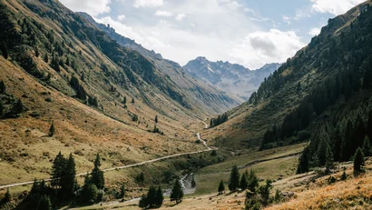 Alpines Tal mit Bergbach, Wanderweg, Nadelwäldern und schroffen Gipfeln