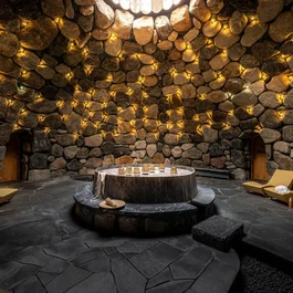Runde Steinhöhle mit warmen Lichtern und zentralem Marmortisch