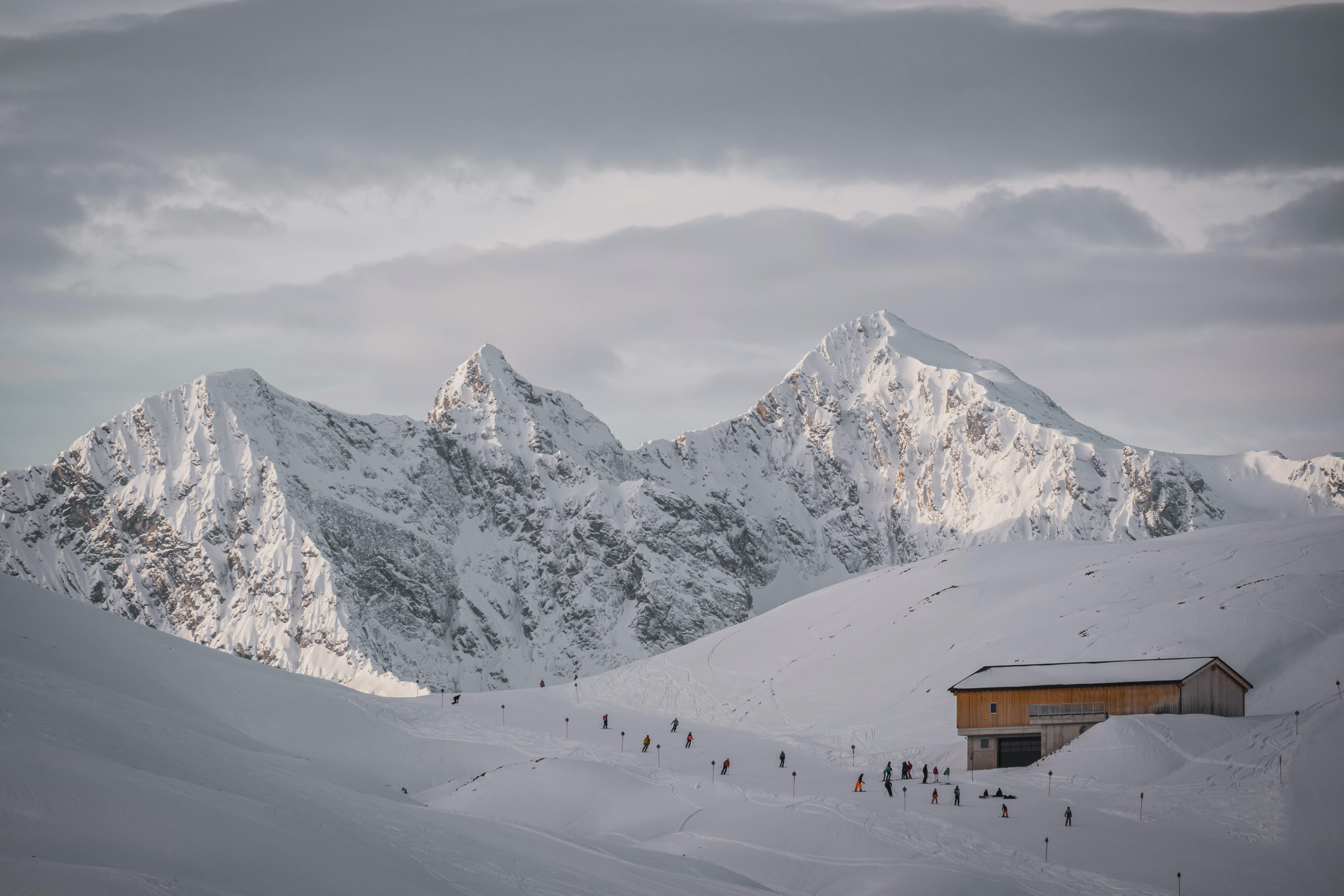 Schneebedeckte Berge mit Skifahrern und einer Hüttenanlage im Winter